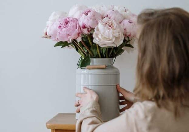 mujer colocando jarron de flores frescas